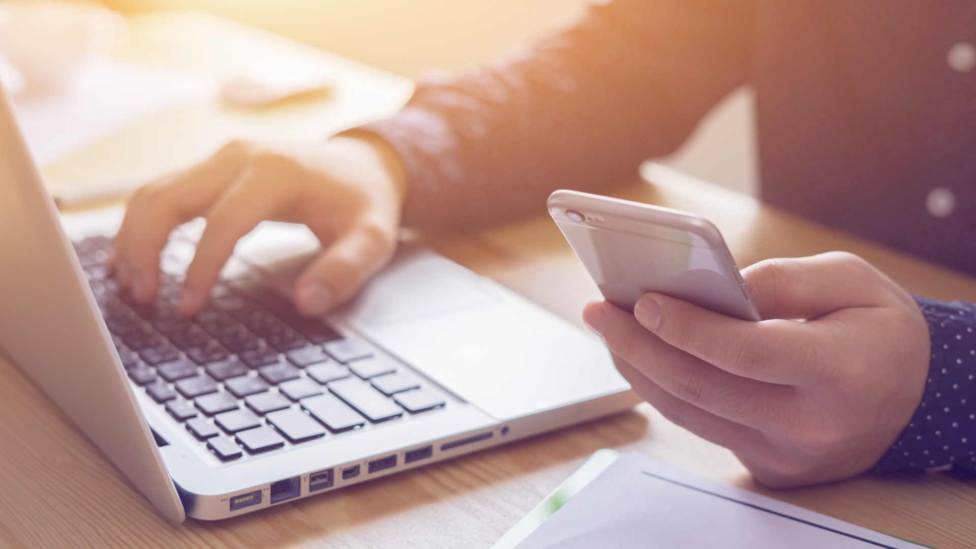 Person working on a laptop and mobile phone